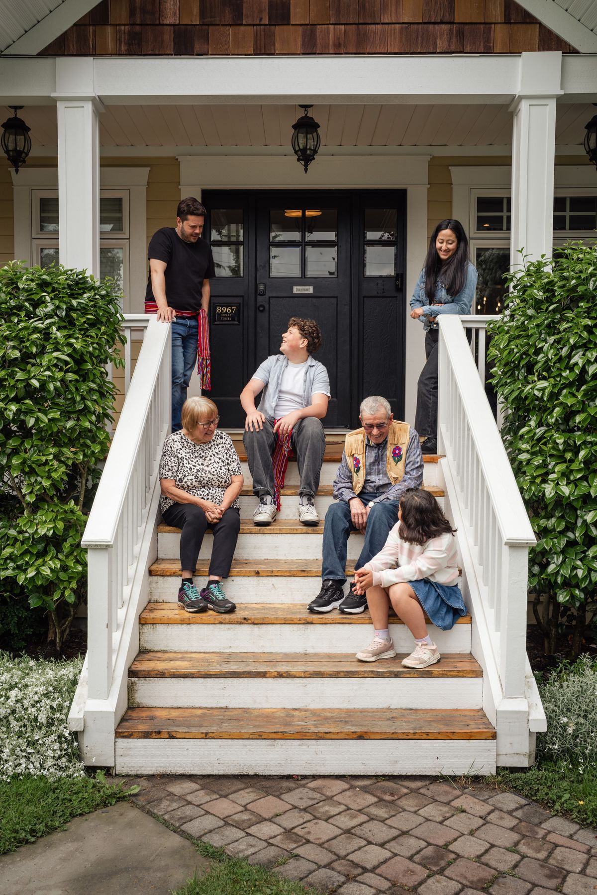 A multi-generational family together on the front porch steps of their home